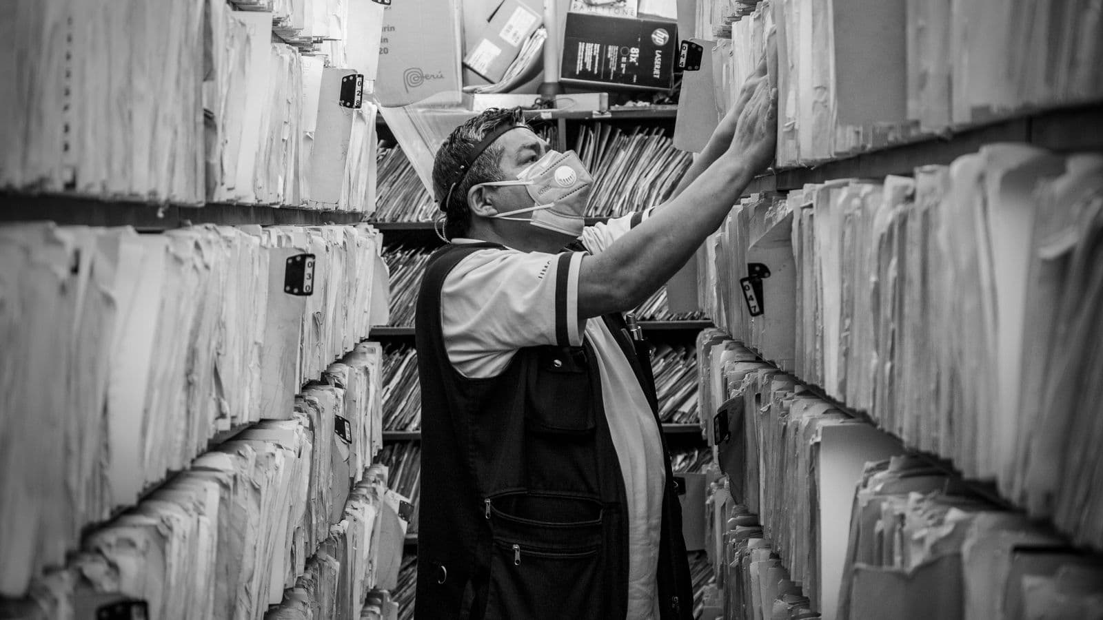 Person sorting through folders of archived invoices on office shelving
