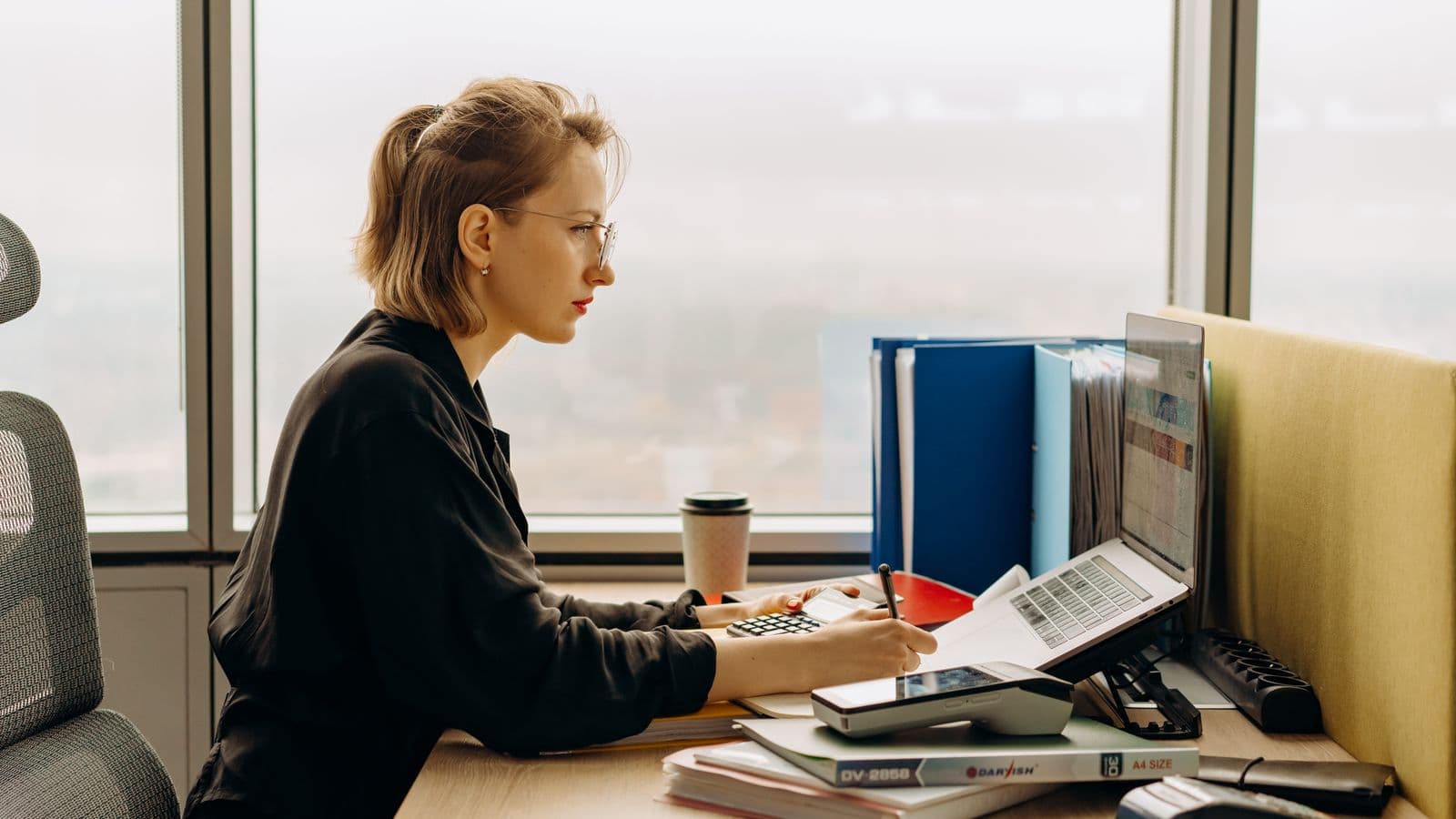 Accountant filing supplier invoices on a laptop, illustrating purchase invoice management in YouInv