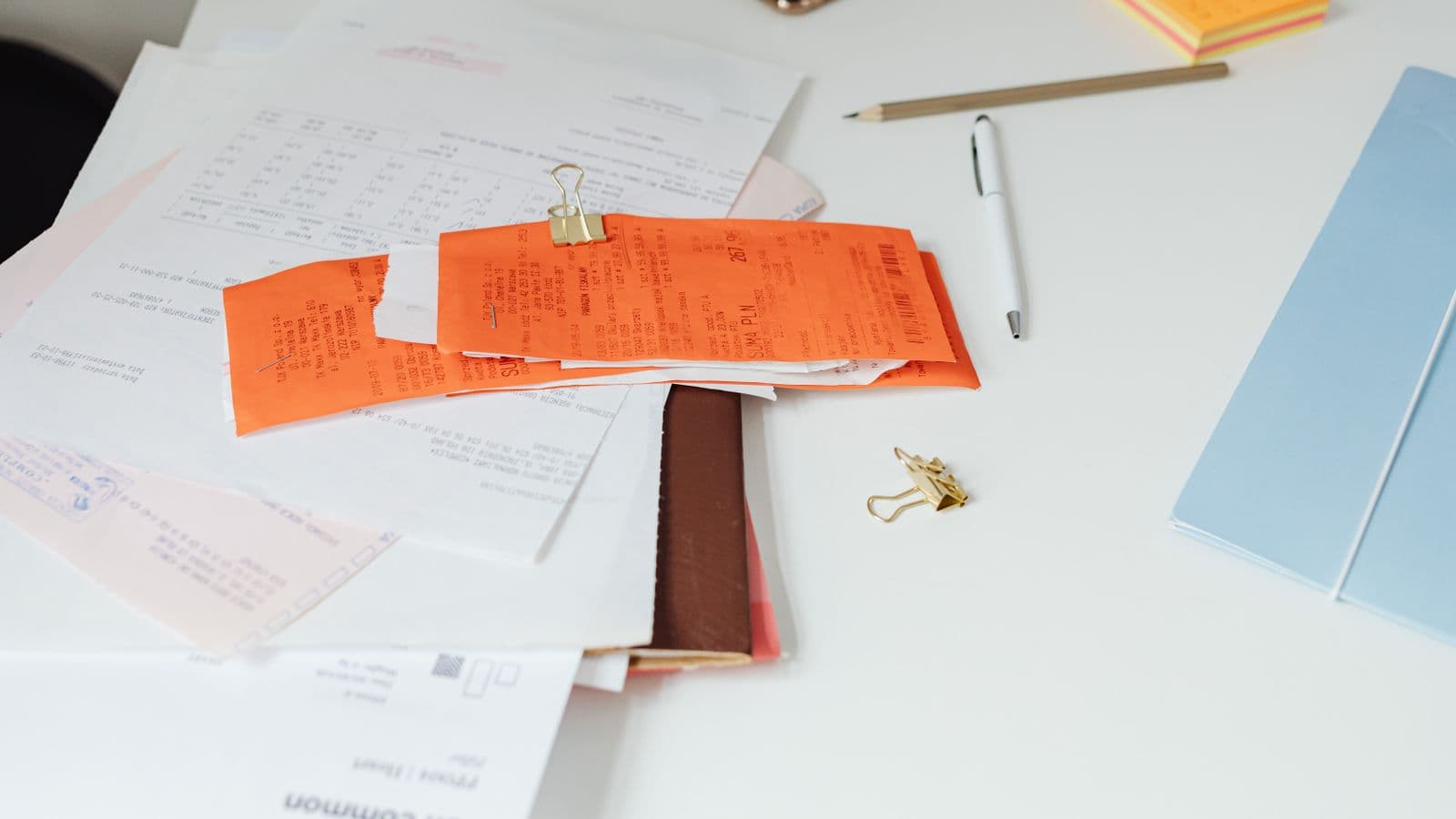 Paperclip op documenten naast een laptop, als illustratie van een bijlage bij een Peppol-e-factuur