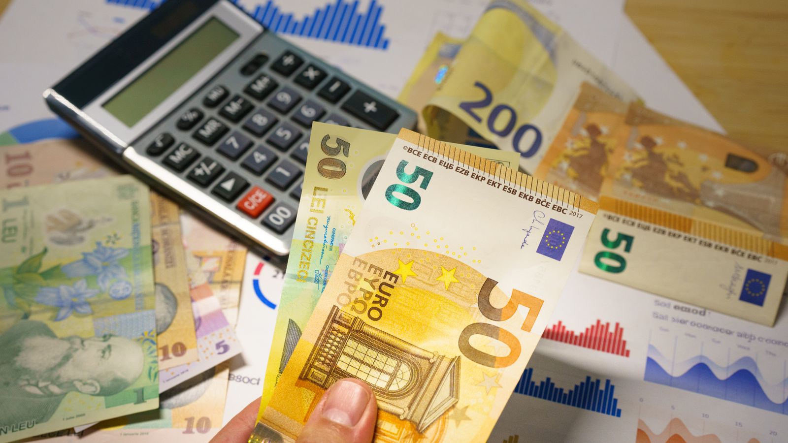 Desk with a calculator and euro and foreign-currency banknotes, illustrating a foreign-currency invoice with VAT converted to euros
