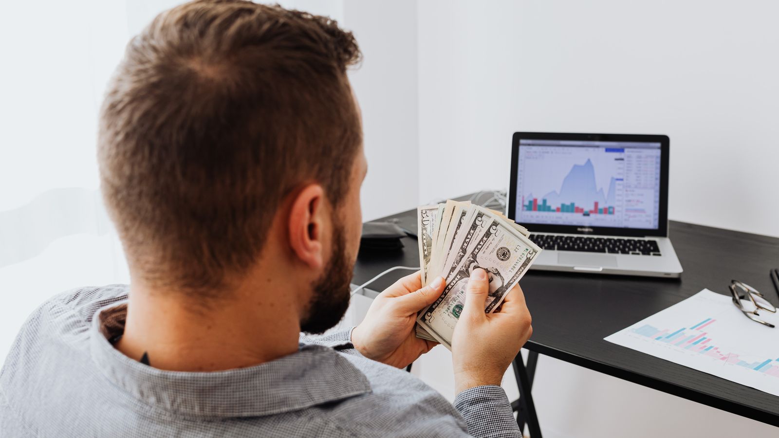 Small business owner reviewing cash flow and receipts on a laptop at a desk